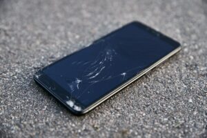 Damaged smartphone with broken touch screen on asphalt